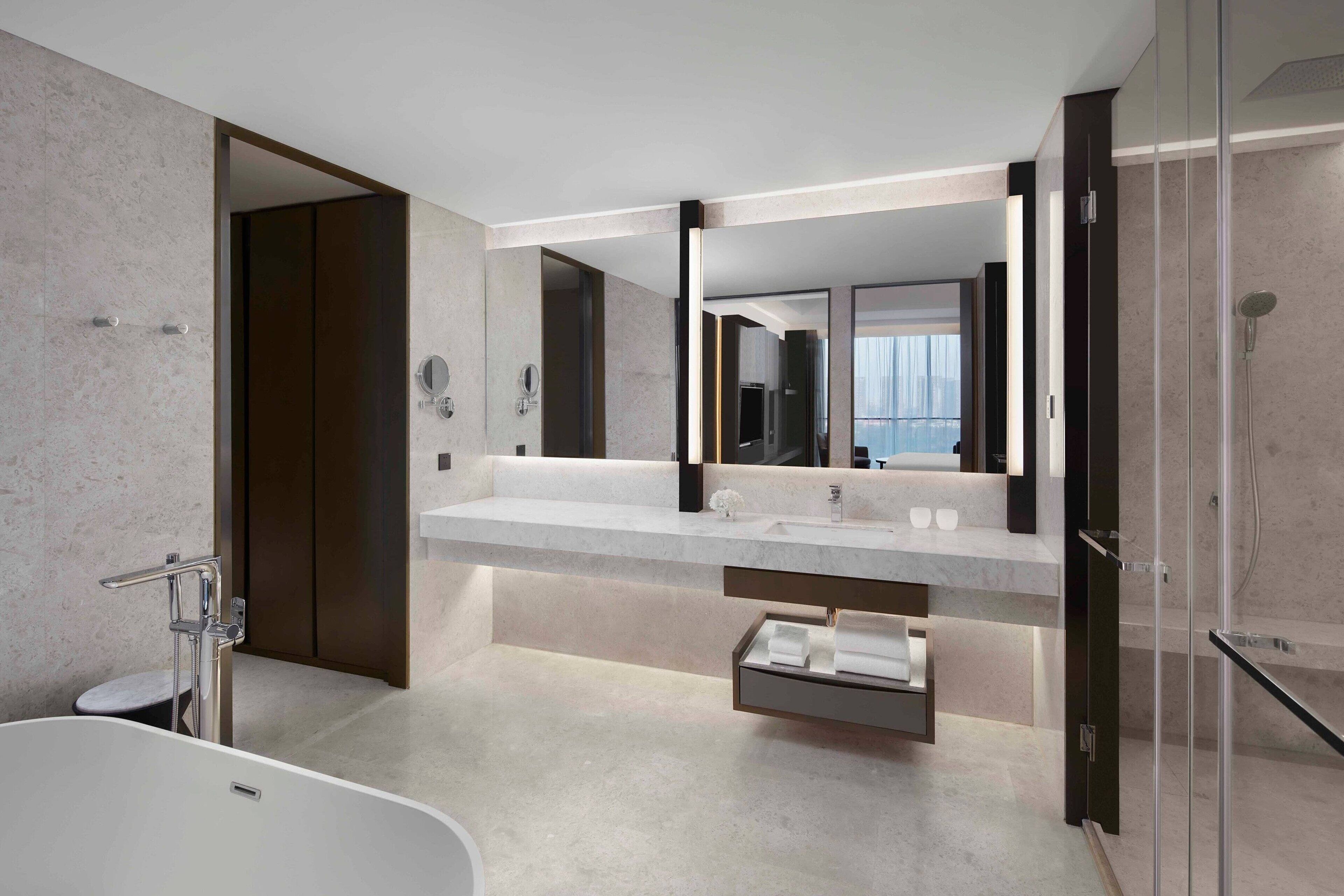 Un baño moderno con un espejo grande, dos lavamanos, una bañera y una cabina de ducha de vidrio.