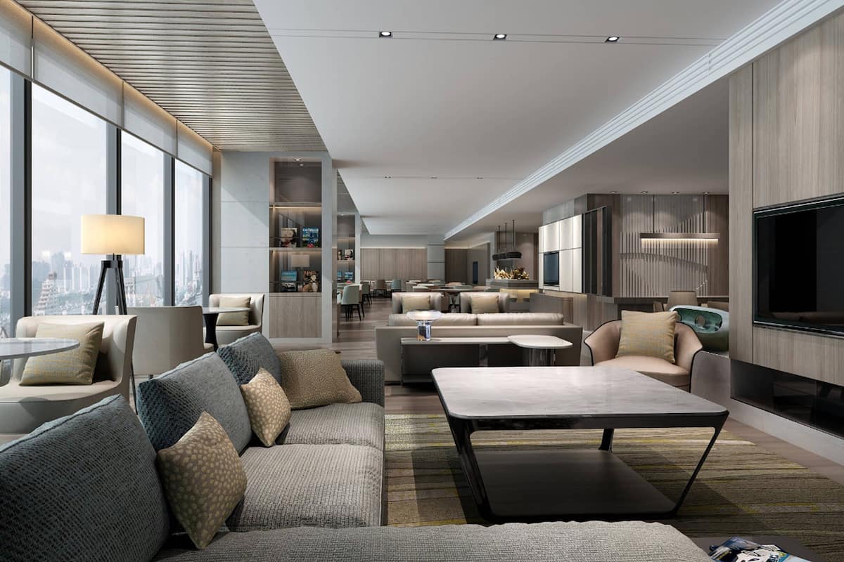A modern hotel lobby with a spacious seating area, a flat-screen TV, and large windows offering a city view.