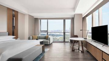 Una habitación de hotel moderna con una cama grande, un sofá, una mesa de comedor y un televisor.