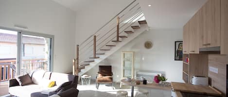 A modern living space with a staircase, a dining area, and a kitchen.