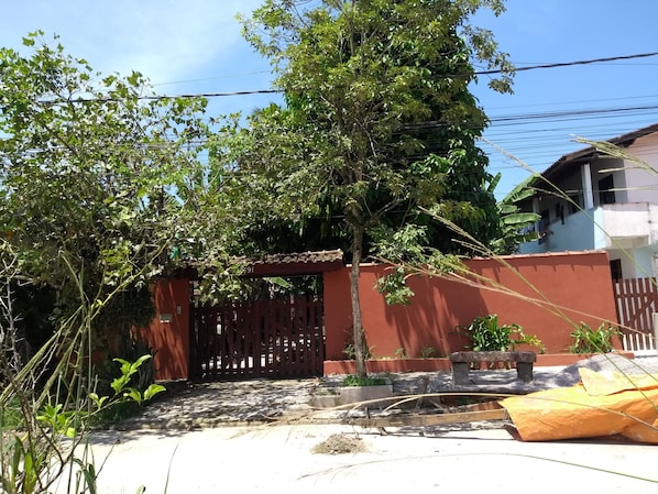 A residential area with a red gate, a tree, and a building in the background.
