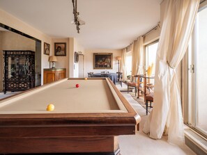 A billiards table with balls, a wooden cabinet, and a painting on the wall.