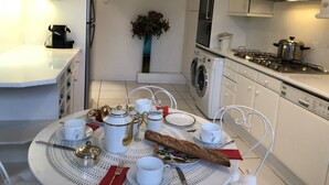 Cocina compacta con comedor, que incluye una mesa dispuesta para una comida con vajilla blanca y hogaza de pan.