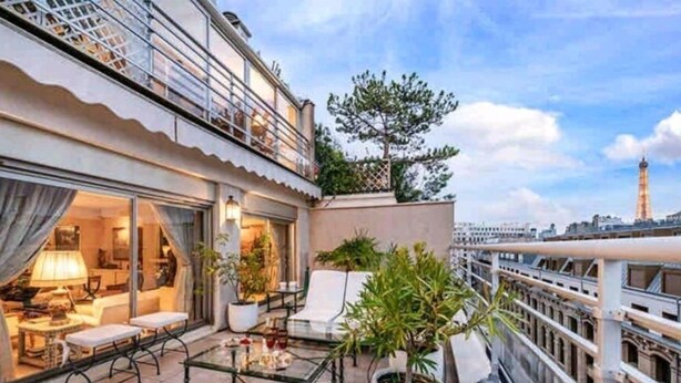 Una terraza en la azotea con mobiliario exterior, plantas en macetas y vistas del horizonte de la ciudad.