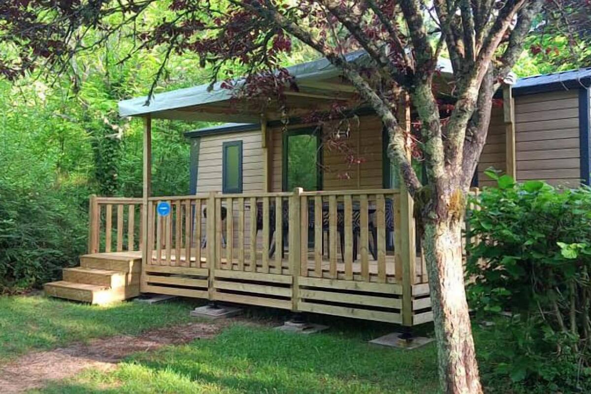 Une petite cabane dotée d’une terrasse en bois et d’un escalier menant à l’entrée.