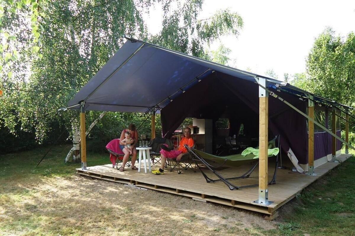 Une tente dotée d’une terrasse en bois et de chaises.