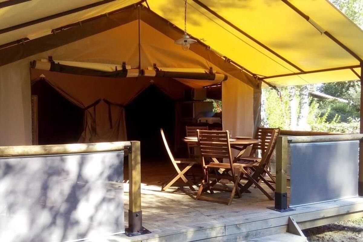 Une tente équipée d’une table et de chaises, d’un luminaire suspendu et offrant une vue sur les environs.