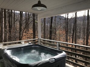 A hot tub with a view of a forested area.