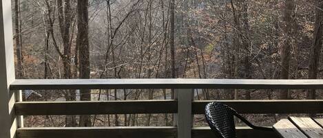 A wooden deck with a bench and a view of a forested area with mountains in the distance.