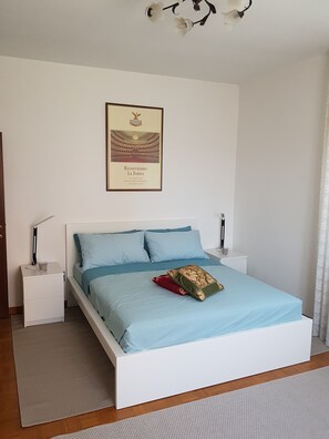 Quarto bem organizado com cama, mesas de cabeceira e um quadro na parede.