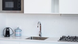 Eine Küche mit Mikrowelle, Spüle, Gasherd, Wasserkocher und einem blauen und weißen Behälter.