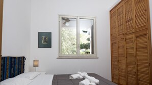 Ein Schlafzimmer mit einem Bett, einem Fenster, einer Nachttischlampe und einem Holzschrank.