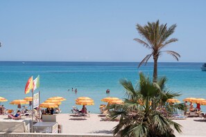 A beach with umbrellas and palm trees.