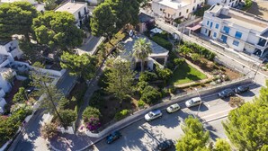 An aerial view of a residential area with houses, trees, and a road with parked cars. - Villa Faro (San Vito Lo Capo)