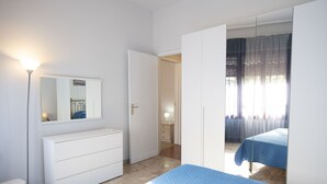 A bedroom with a bed, a dresser, a mirror, and a door leading to another room. - Villa Faro (San Vito Lo Capo)