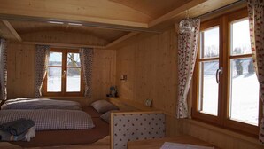 A cozy wooden cabin room with two beds, a bench, and large windows with curtains. - Schäferwagen am Berghof (Zeulenroda-Triebes)