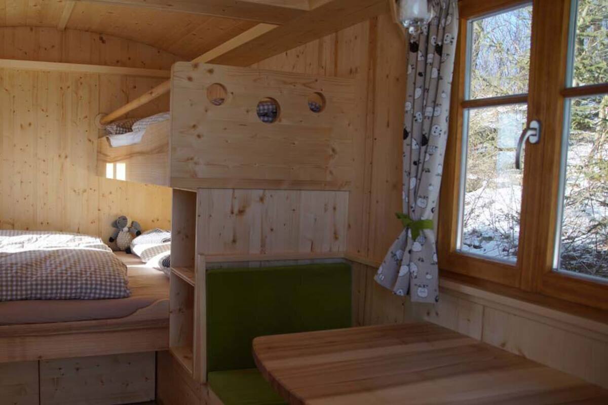 Ein gemütliches Blockhaus mit einem Etagenbett, einer grünen Bank und einem Holztisch.