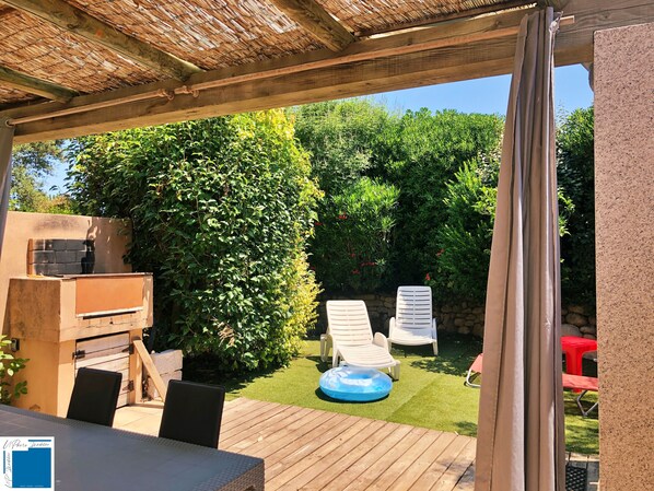 A wooden deck with a grill, two lounge chairs, and a small inflatable pool.