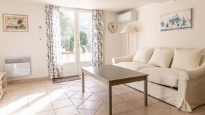 A living room with a sofa, a coffee table, a lamp, and a window with curtains.