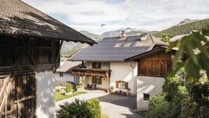 A traditional chalet with a sloped roof, solar panels, and a small balcony with potted plants. - The Dorfblick vacation apartment with south-facing balcony two bedrooms, two bathrooms (Rodneck)