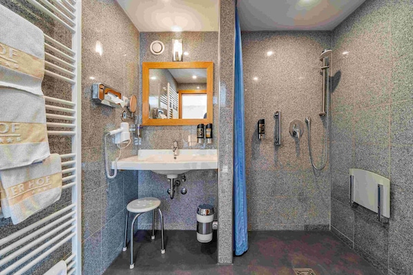 A bathroom with a sink, mirror, towel rack, and shower. - Hotel Hagnauer Hof (Hagnau)