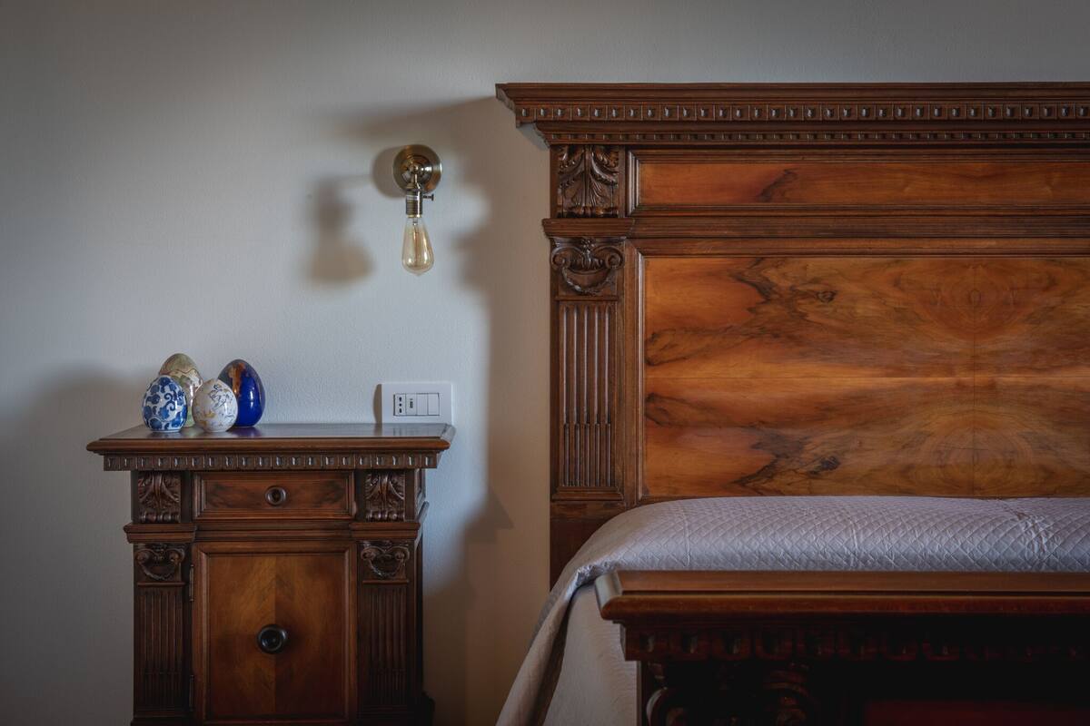 Un lit en bois avec une tête de lit, une table de chevet avec une horloge et des vases décoratifs.