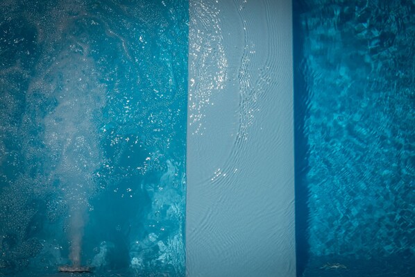 A pool with clear water, a tiled wall, and a textured surface.