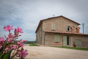 A stone house with a gravel driveway and a green lawn.