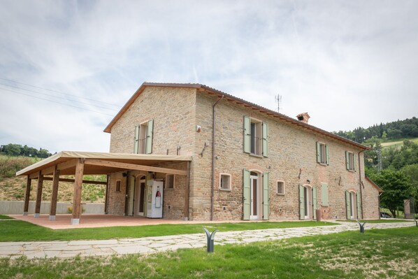 A stone building with a covered patio and multiple doors.