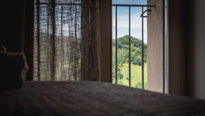 A bedroom with a large window overlooking a green landscape. - Agriturismo Podere Ceriano (Modigliana)