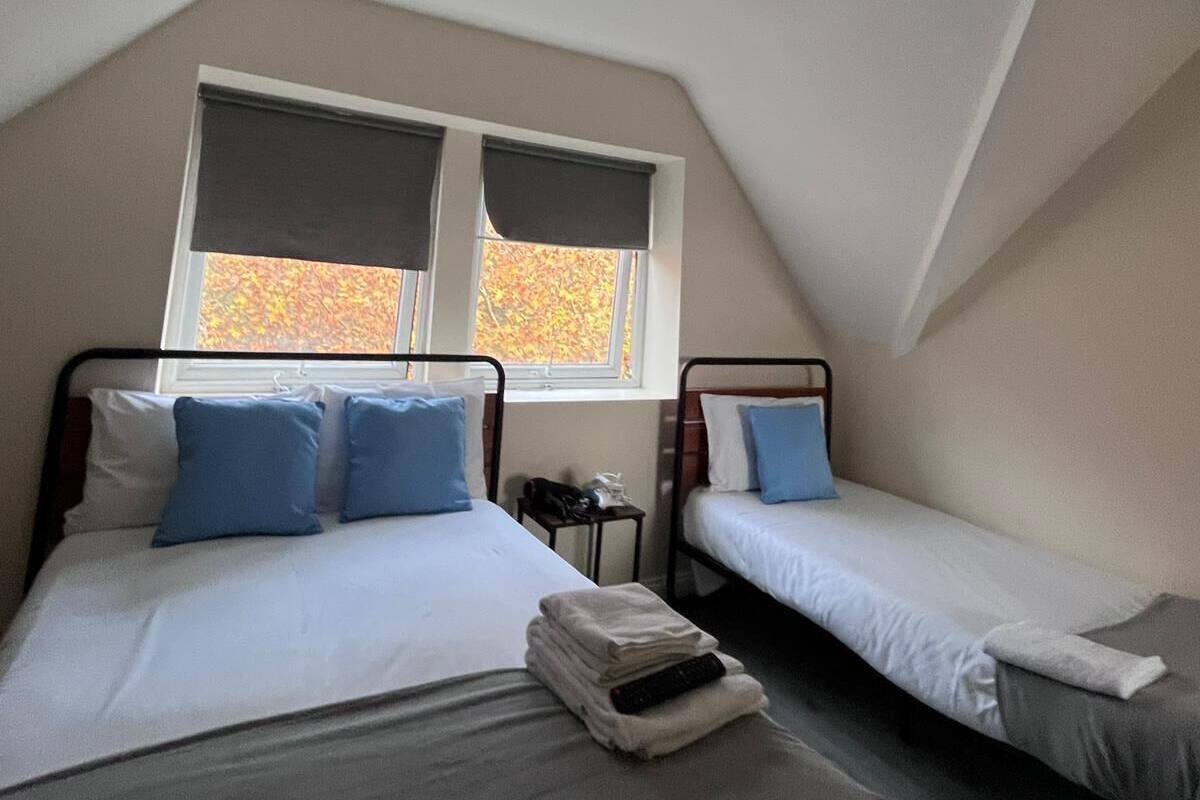 A dormitory room with two beds, a window, and a small table.