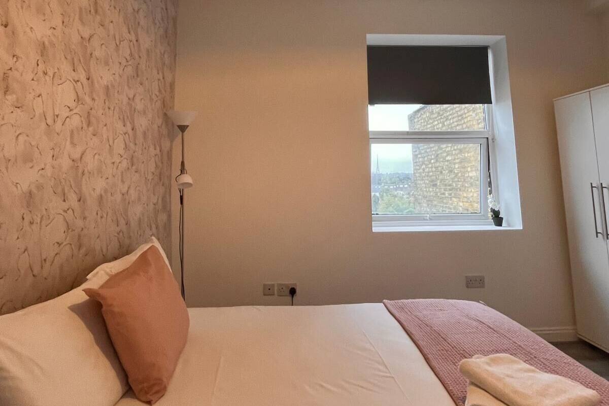 A bedroom with a bed, a window, a wall-mounted light fixture, and a wardrobe.