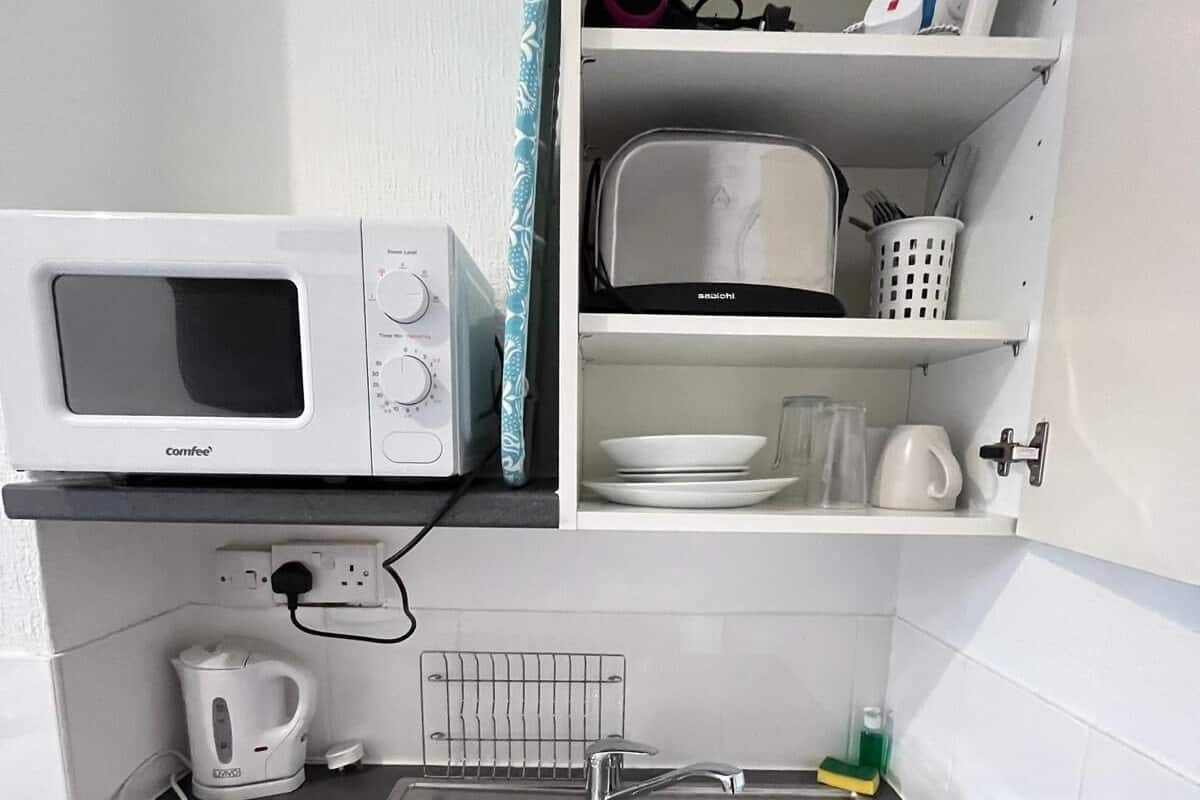 A compact kitchen with a microwave, toaster, and sink.