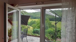 A room with a sliding glass door leading to an outdoor patio with a chair and a table. - Apartment in the countryside (Beilstein)