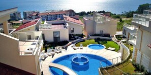 Ett bostadskomplex med en swimmingpool och utsikt över havet.