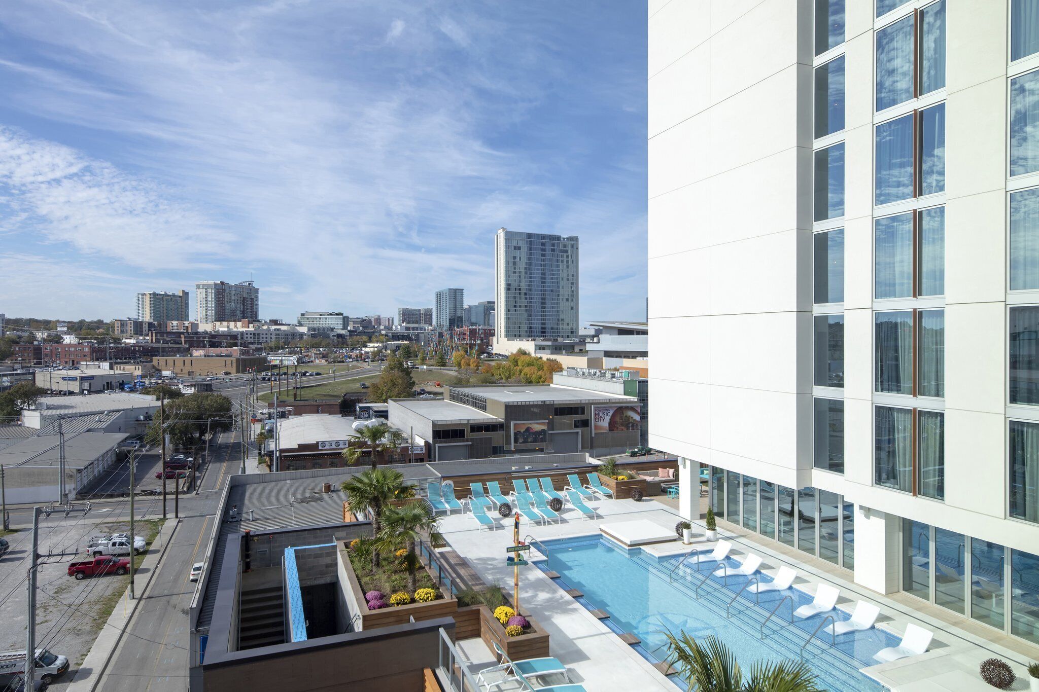 Piscina no terraço com espreguiçadeiras, vista do horizonte da cidade e edifícios modernos.