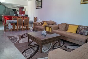 A living room with a sofa, coffee table, and dining area with chairs and a table.