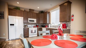 Una cocina moderna con armarios de madera, un refrigerador blanco, un microondas y una mesa de comedor con individuales rojos.