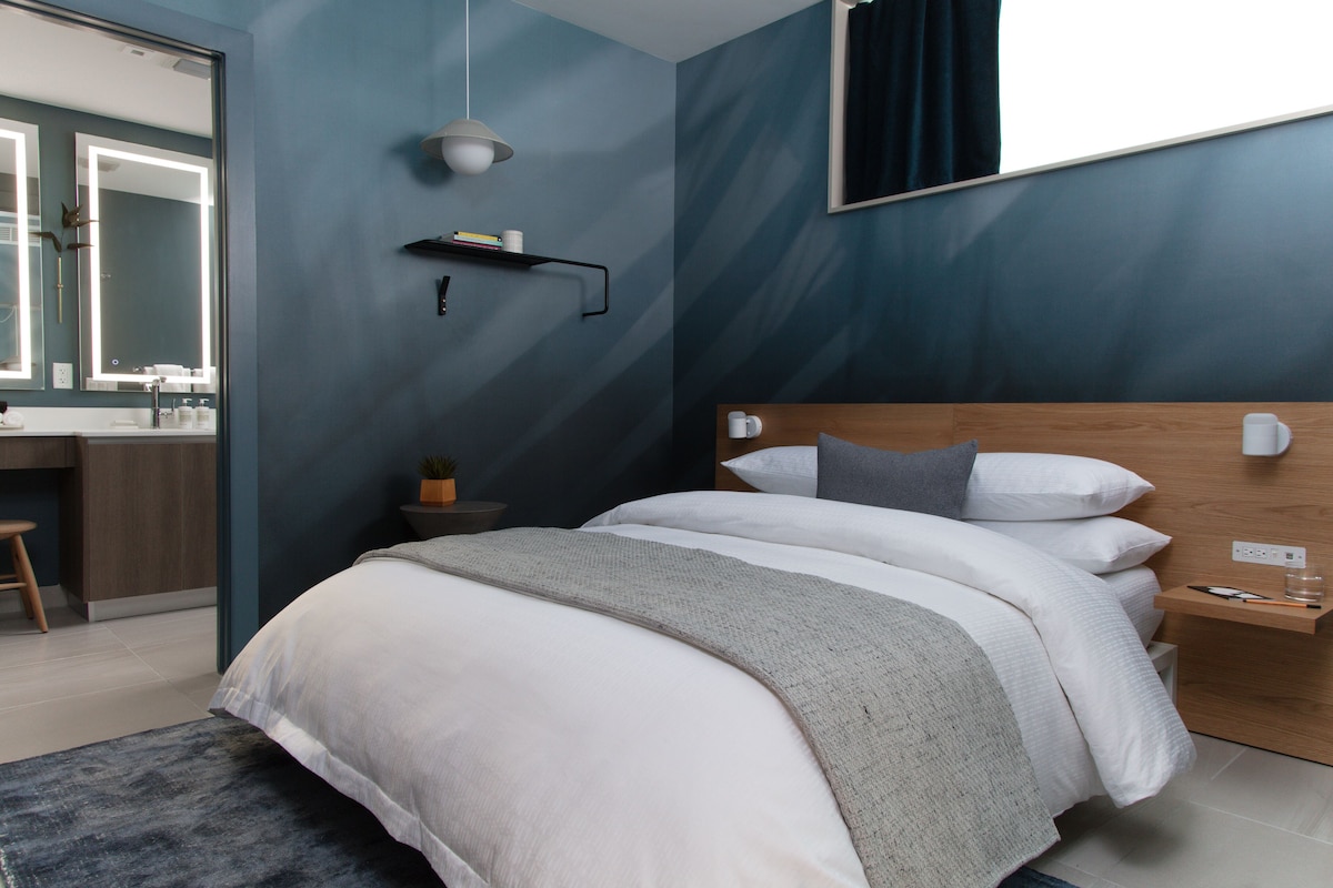 A modern bedroom with a large bed, bedside table, and a nightstand.