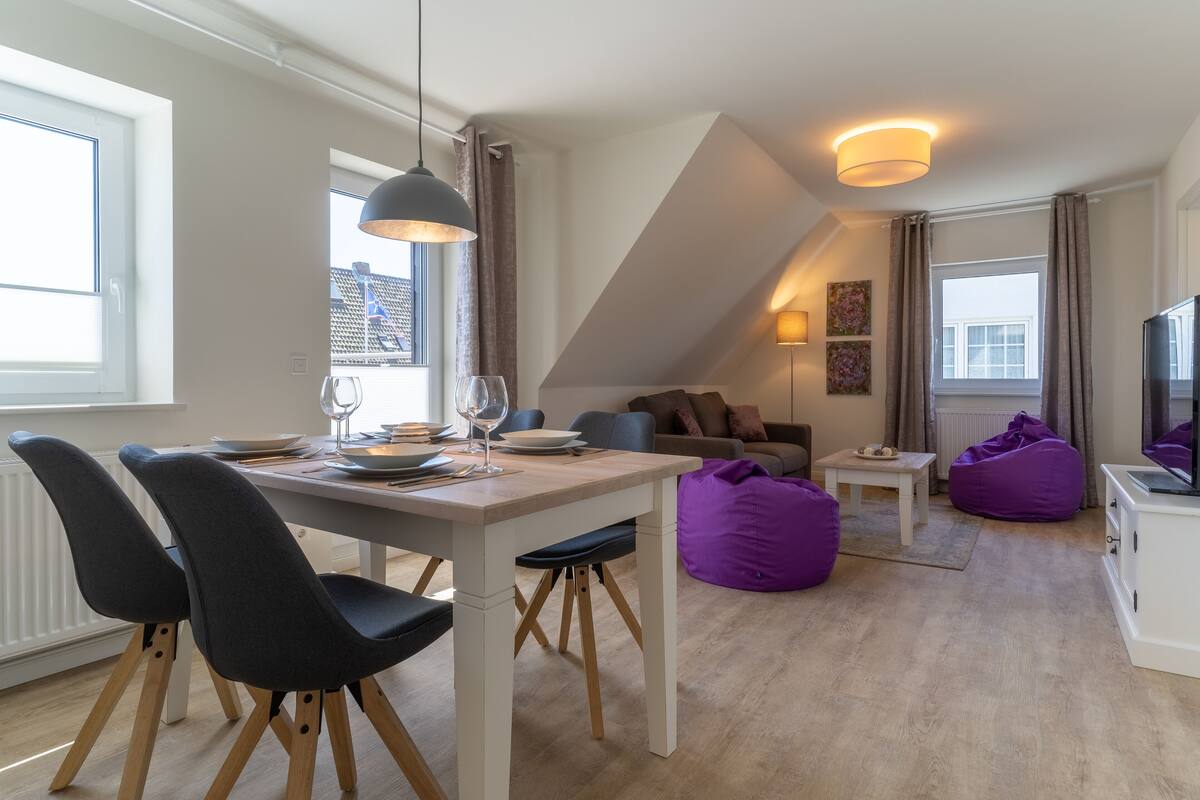 Una sala de estar moderna con comedor, un sofá y un televisor.