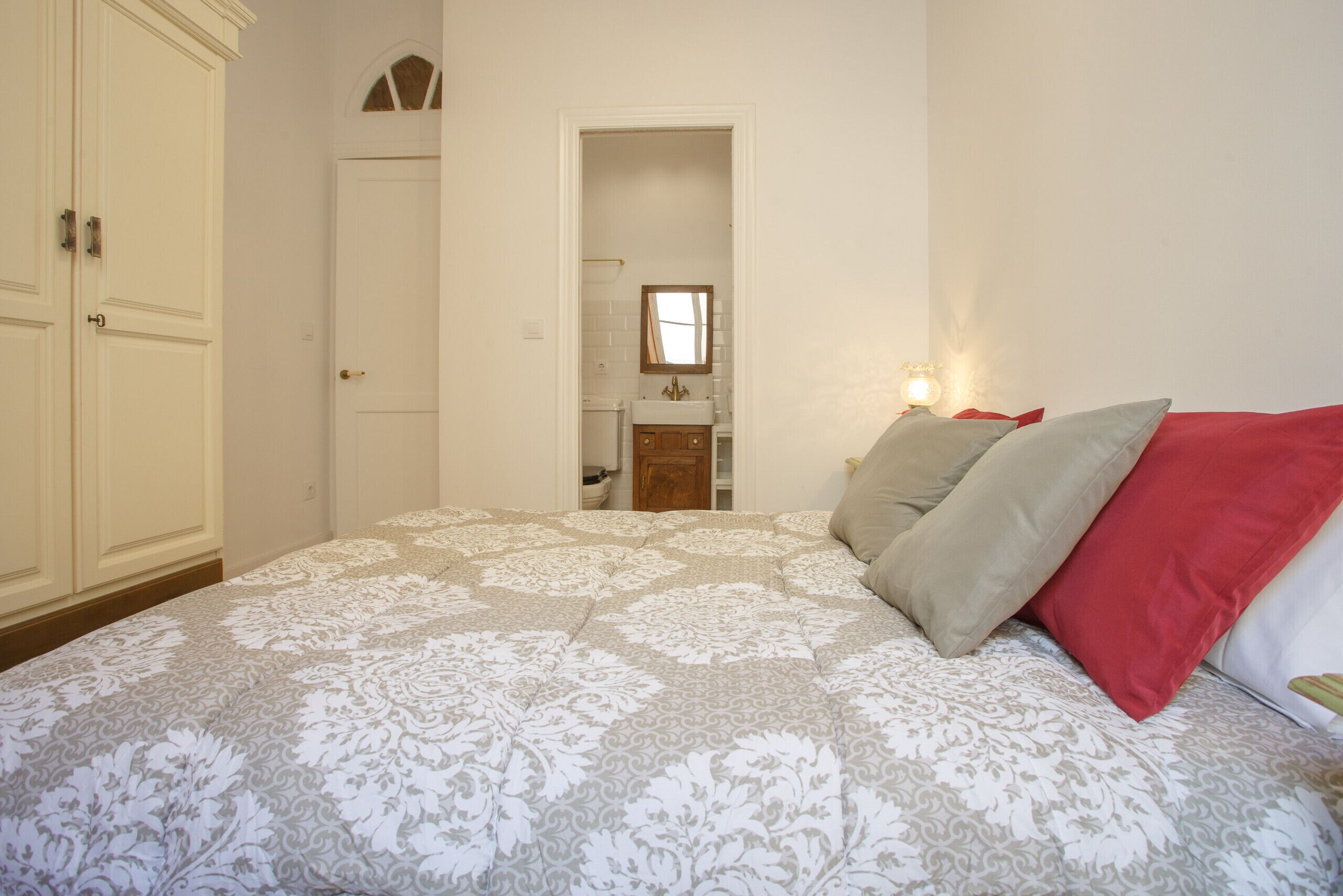 A bedroom with a bed, a wardrobe, and a bathroom visible through an open door.