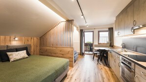 Une chambre à coucher moderne avec une tête de lit en bois, une couvre-lit verte et un escalier en bois menant à un balcon.
