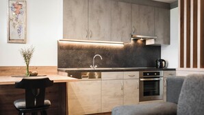 Une cuisine moderne dotée d’un four encastré, d’appareils électroménagers en acier inoxydable et d’un coin repas en bois.