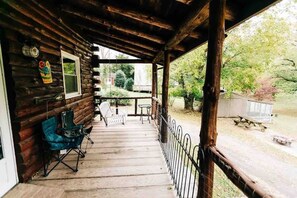 Een houten hut met een veranda, een tafel en twee stoelen.