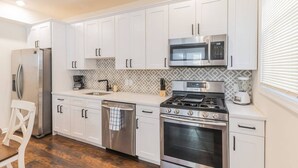 A modern kitchen with white cabinets, stainless steel appliances, and a patterned backsplash. - Amazing Beach house  with 2 Units booked together (Ventnor City)