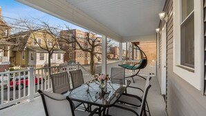A covered balcony with a glass table, chairs, and a hanging chair. - Amazing Beach house  with 2 Units booked together (Ventnor City)