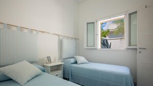 Een slaapkamer met twee bedden, een raam met uitzicht en een nachtkastje met een lamp.