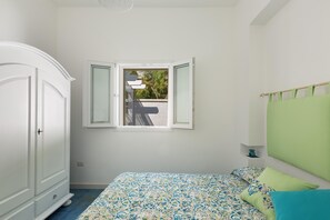 Une chambre à coucher avec un lit, une armoire, une fenêtre et une vue sur l’extérieur.