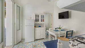 Een kleine keuken met een gasfornuis, witte kasten en een betegelde vloer.
