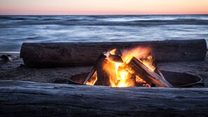 A campfire on a beach at sunset.
